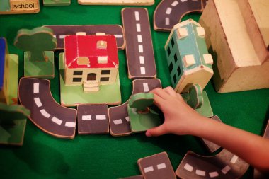 Ağaçları, yolları ve binaları olan ahşap bloklardan bir şehir inşa eden bir çocuğun manzarası..