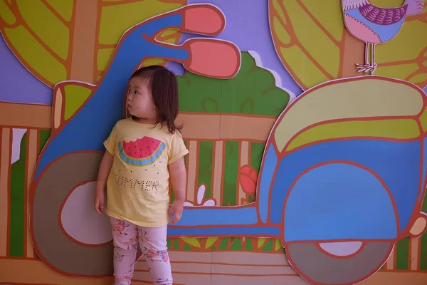 El yapımı scooter duvar kağıdının önünde mutlu ve gülümseyen sevimli bir Asyalı kız..