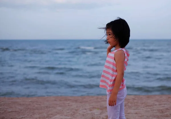 Yalnız, tatlı bir Asyalı kız sahilde tek başına dikiliyor, uzak diyarlara bakıyor, derin düşünceler içinde..