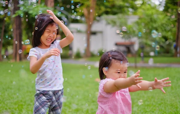 Two Cute Asian Sisters Playing Bubbles Park Green Grass Laughing — Stock Photo, Image
