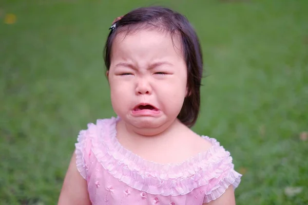 Funny face of a sad little Asian girl crying, frowning.