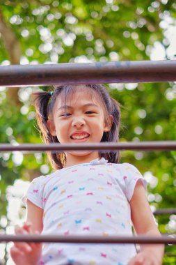 Bir üst geçitten aşağıya bakan tatlı bir Asyalı kız mutlu ve gülümsüyor..