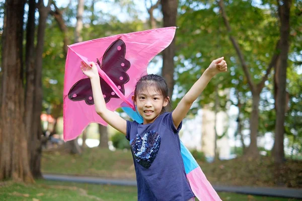 Tayland 'da yeşil bir çimenlikte uçurtmasıyla oynayan genç bir Asyalı kız..
