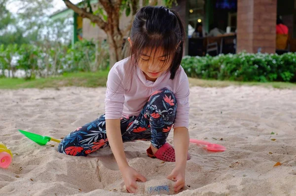 Kum havuzunda oynayan sevimli bir Asyalı kız.. 