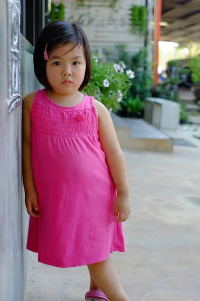 Симпатичная Азиатка Розовом Платье Прислонившаяся Бетонной Стене Дующаяся — стоковое фото