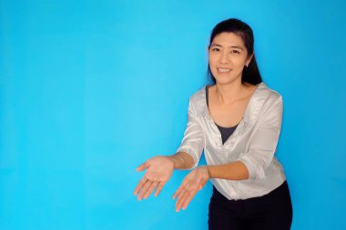 30 'lu yaşlarda çekici bir Asyalı kadının açık mavi arka planda bir ürünü sergilediği belden yükseklik çekimi..