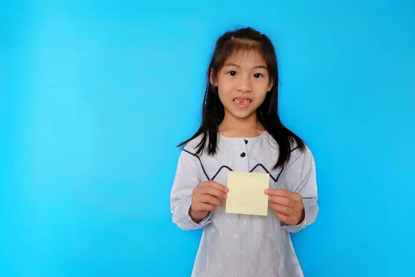 Açık mavi arka planda duran, elinde boş bir kağıt parçasıyla gülümseyen genç bir Asyalı kız..