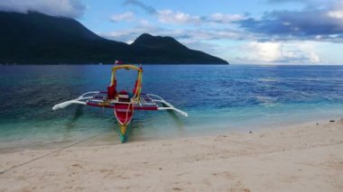 Beyaz kum plaj beyaz Island Camiguin, geleneksel bir tekne (banca) ile karşı karşıya, kıyıya bağlı. Aktif yanardağ Hibok Hibok (olarak da bilinen Catarman volkan) Mount arka planda görülebilir.