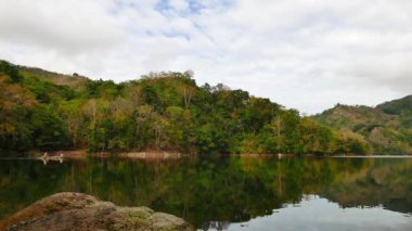 Dağ gölü Balanan pastoral güzelliği Negros Oriental, Filipinler'de gösterilen bir gerçek zamanlı klip. O yansıtan bir ayna gibi sahne sakin bir göldür. Yerel bir ikamet arasında geleneksel Avara Demiri kürek çekmeye görülebilir.