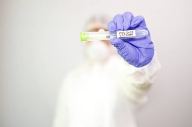 Üzerinde Coronavirus aşısı olan bir şırınga bulunan mavi cerrahi eldivenli mikrobiyolog ya da tıp çalışanı elinin yakın çekimi. COVID-19 aşı konsepti