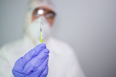 Mavi eldivenli mikrobiyolog ya da tıp çalışanı hızla yayılan Coronavirus aşısı şırıngasını tutuyor. COVID-19 aşı konsepti