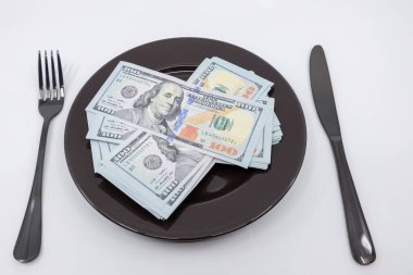 Çatal ve bıçakla dolu yüzlerce dolarlık banknotlar. Refah ve bolluk kavramı. Tam tabak konsepti. Boşluğu kopyala