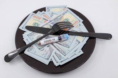 Yüzlerce dolarlık banknotları çatal, bıçak ve pozitif COVID-19 testi ile doldurun. Coronavirüs salgınının konsept maliyeti. Coronavirus uyarıcıları konsepti kontrol eder.