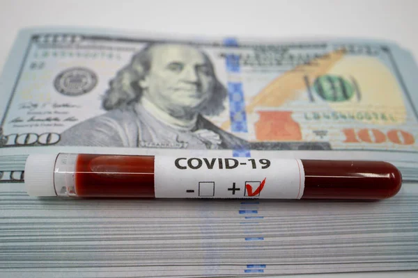 Yüz dolarlık banknotların üstüne kovid 19 kan örneği tüpü. Mali Kriz Ekonomik Borsa Bankacılık Konsepti Yeni bir salgın nedeniyle
