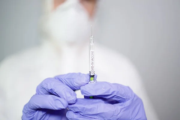 Mavi eldivenli mikrobiyolog ya da tıp çalışanı hızla yayılan Coronavirus aşısı şırıngasını tutuyor. COVID-19 aşı konsepti