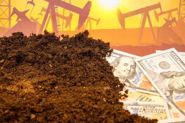 Oil industry crisis concept. Drop in crude oil prices. Hundreds of dollar bills under dirt.