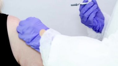 Mavi ameliyat eldivenli bir mikrobiyolog ya da tıp çalışanı aşıyı hızla yayılan Coronavirus için bir şırıngayla birine veriyor. COVID-19 aşı konsepti