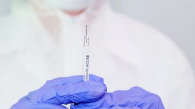 Mavi eldivenli mikrobiyolog ya da tıp çalışanı hızla yayılan Coronavirus aşısı şırıngasını tutuyor. COVID-19 aşı konsepti