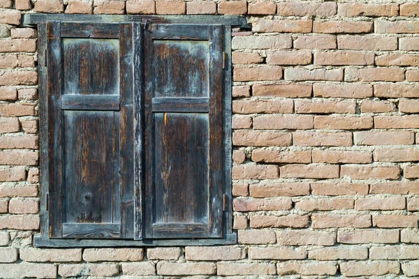 Eski, pasaklı, kırmızı tuğla duvar dokusu ve yaştan sonra bozulma. Eski tuğla duvardaki eski ahşap pencere.