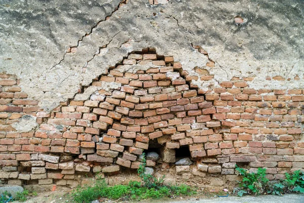 Eski, pasaklı, kırmızı tuğla duvar dokusu ve yaştan sonra bozulma. İçinden ot çıkan eski tuğla duvar.