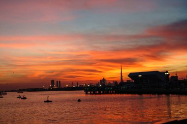 Dubai ufuk çizgisinin güzel manzarası golf suyunda yansıması ve kırmızı, sıcak bir günbatımının muhteşem renkleri. Güzel zamanlar kavramı.