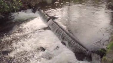 Bereketli bir dereyle vahşi dağ nehri şelalesine yakın. Taştan kayalar ve akan su ile kabarcıklı derenin statik görüntüsünü detaylandır. Hızla akan suda kayalar hızlanır..