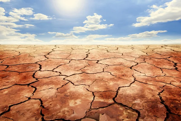 Suelo seco agrietado en tierra de sequía bajo el cielo azul . — Foto de Stock