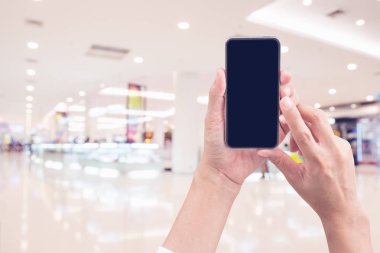 Kadının ve akıllı telefon ile tutarak süpermarket arka plan bulanıklık