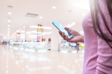 Kadının ve akıllı telefon ile tutarak süpermarket arka plan bulanıklık