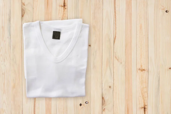 Vue du dessus du T-shirt blanc sur fond de table en bois — Photo