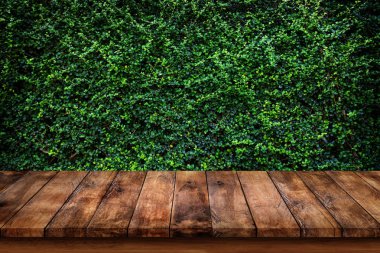 Boş eski ahşap masa veya sayaç yeşil yaprakları arka plan ile.