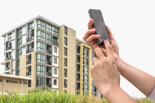 Hand met een slimme telefoon en nieuwe condominium. — Stockfoto