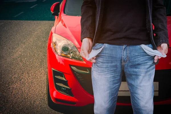 Mann zeigt leere Taschen mit rotem Auto-Hintergrund. — Stockfoto