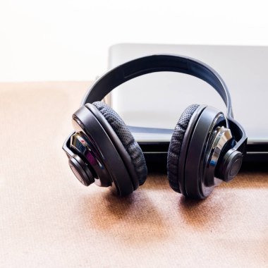 Kulaklık ve ahşap masa üstünde laptop.