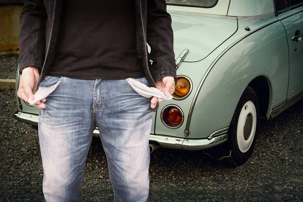 Man showing his empty pockets with classic car background. — Stock Photo, Image