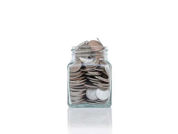Szklane słoiki z monet na powierzchni odbijającej na białym tle. — Zdjęcie stockowe