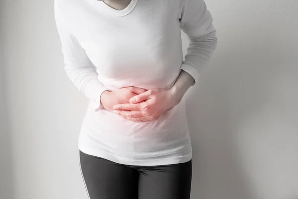 Dolor de estómago de la mujer sobre fondo de pared gris . —  Fotos de Stock