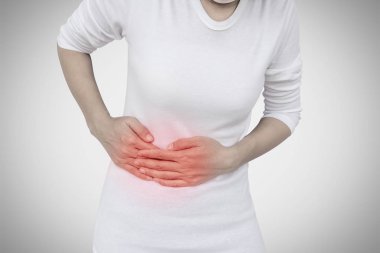 Gri duvar arka plan üzerinde kadın mide ağrısı.