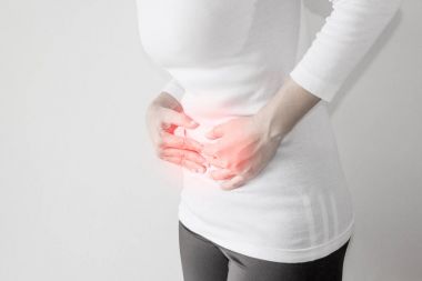 Gri duvar arka plan üzerinde kadın mide ağrısı.