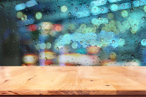 Pusty top drewna stołu z kropla na okno w deszczową noc miasta — Zdjęcie stockowe