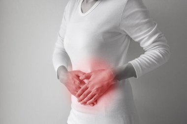 Gri duvar arka plan üzerinde kadın mide ağrısı.