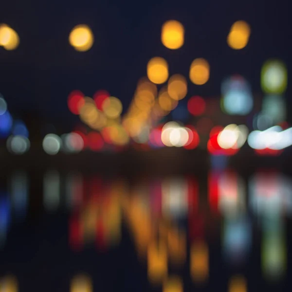 Blurred city lights with bokeh on water — Stock Photo, Image