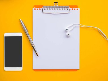 Boş not defteri, kalem, kulaklık ve smartphone sarı