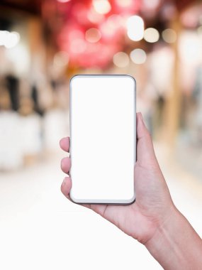 Soyut bulanık alışveriş merkezinin arka planına sahip akıllı telefonu tutmak.