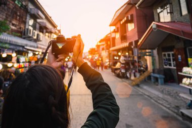 Yürüyen sokakta kamerayla fotoğraf çeken genç bir gezgin..
