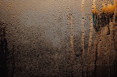 Gece şehir planında araba camına yağmur damlaları.