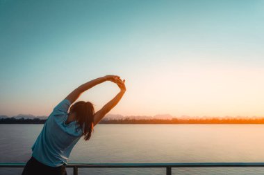 Kadın sabah nehir manzaralı koşudan sonra dinleniyor..