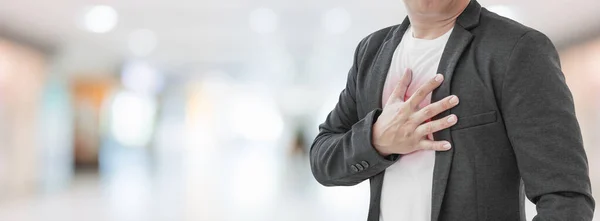 抽象的なぼやけた病院の背景に心臓発作を持つビジネスマン — ストック写真
