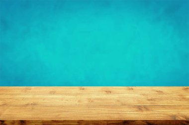 Bulanık mavi duvar arkaplanı olan ahşap masanın üstü boş.