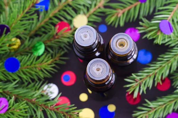 Tre bottiglie di olio essenziale e rami di abete. Aromaterapia natalizia e concetto di spa . — Foto Stock